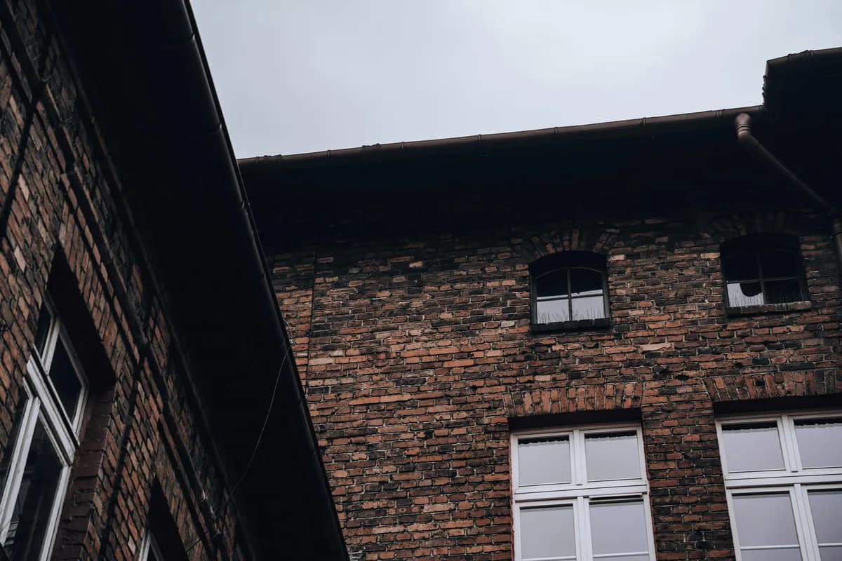 Brick building exterior with white-framed windows and metal roof detail