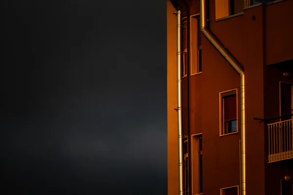 Orange building facade with windows and metal downspouts at night