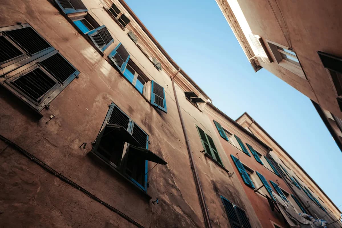 Weathered brick building facade with blue-shuttered windows needing cleaning maintenance