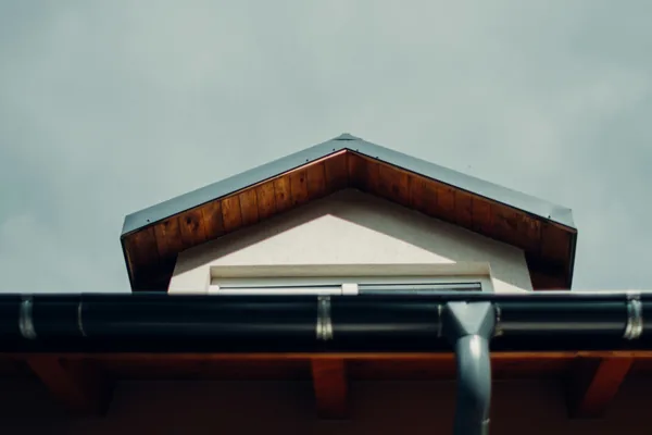 Modern house roofline with metal gutter and white gable window detail