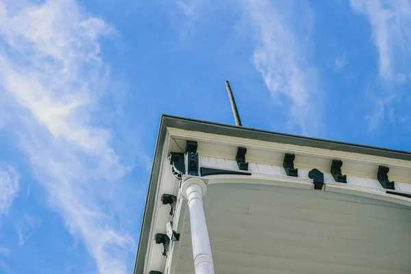 Worker on ladder cleaning exterior windows of white building against blue sky