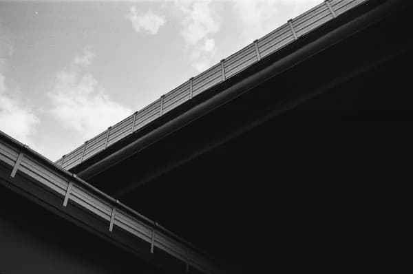 Underside view of concrete highway bridge with metal railings and support structure