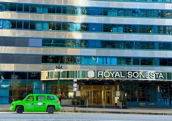 Modern glass and stone building facade with reflective windows and green taxi