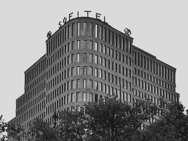 Curved modern office building with repetitive window pattern and vegetation