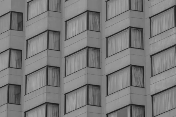 Modern apartment building facade with rows of clean windows and curtains