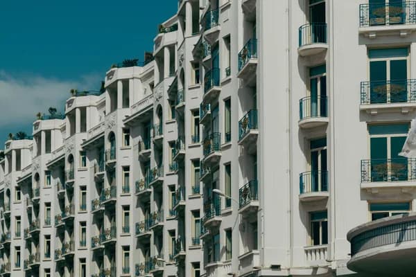 White ornate apartment buildings with teal balconies and decorative ironwork railings