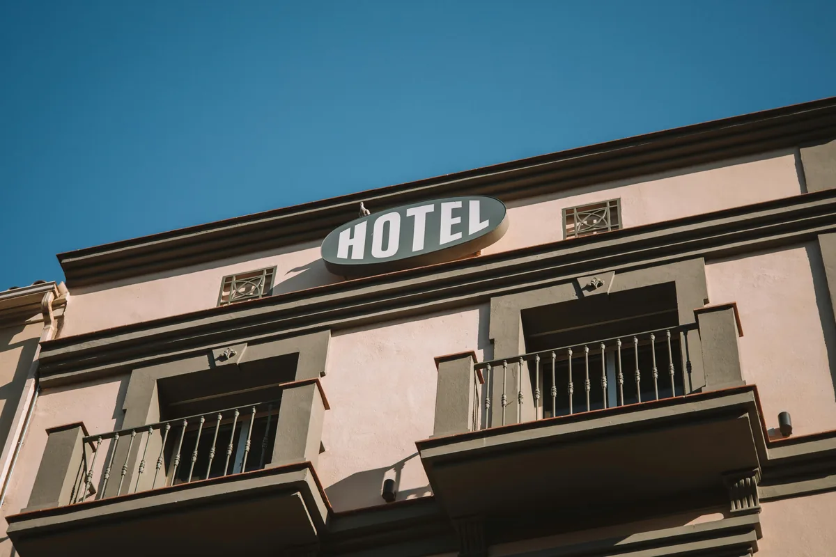 Pink hotel building facade with multiple balconies and windows under clear sky