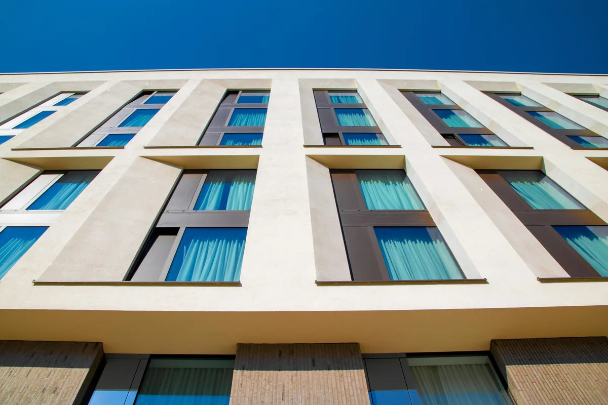 Modern residential building facade with multiple rows of clean windows and blue sky