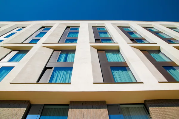 Modern residential building facade with multiple rows of clean windows and blue sky