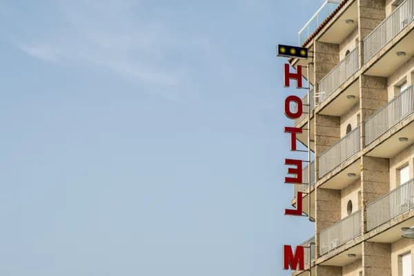 Vertical hotel sign on multi-story building facade with balconies