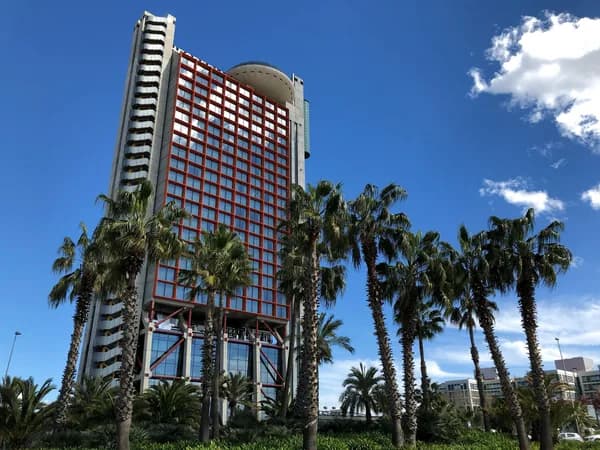 Modern high-rise building with extensive glass windows and palm trees