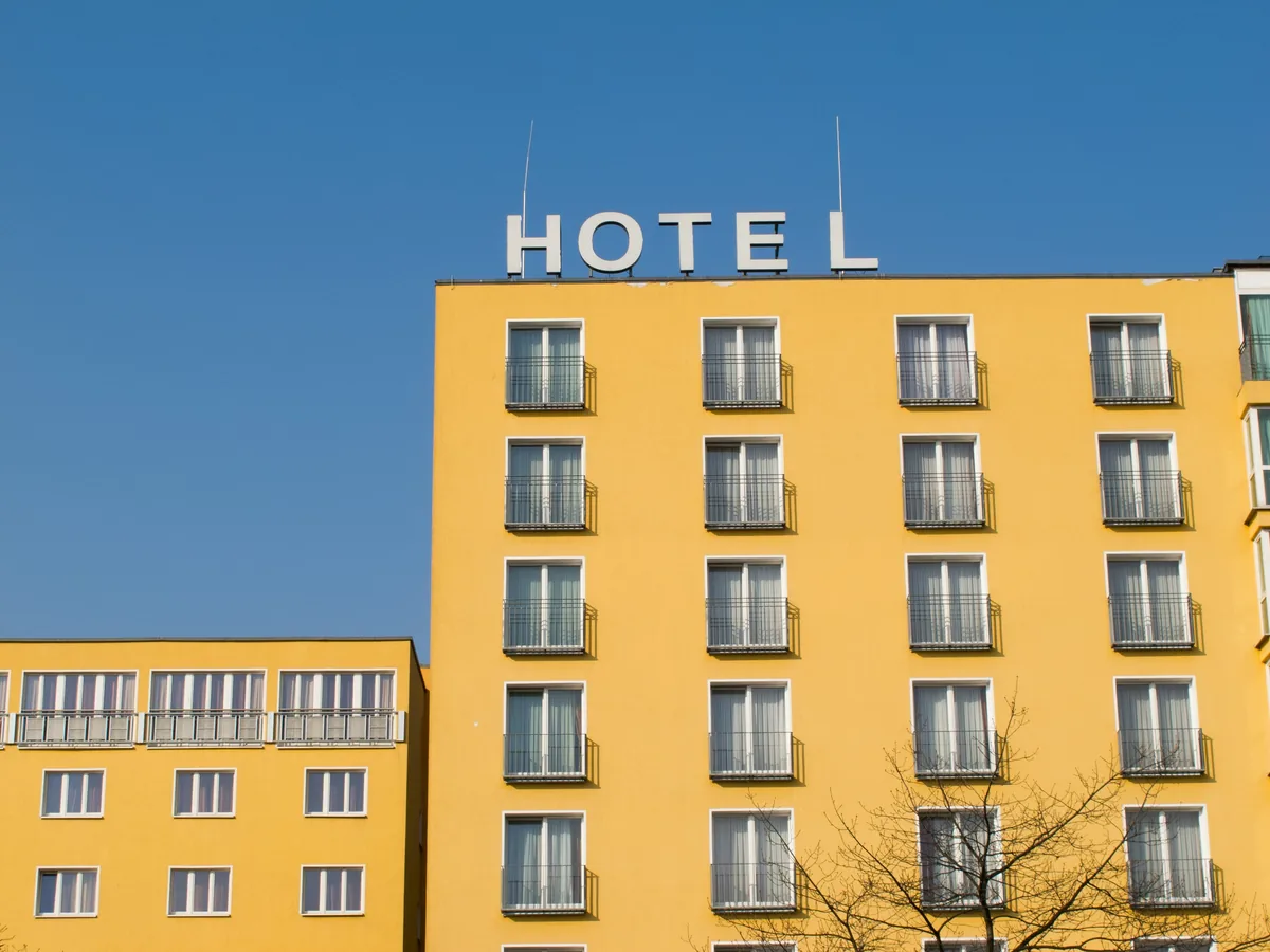Bright yellow hotel building with rows of windows and metal railings