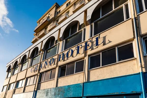 Historic building facade with multiple arched windows and deteriorating blue metal panels