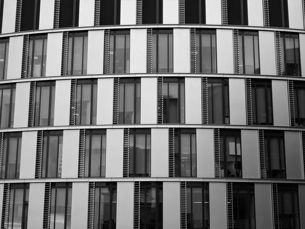 Modern curved building facade with numerous rows of clean windows and dark frames