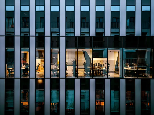 Modern office building facade with illuminated windows and vertical white stripes