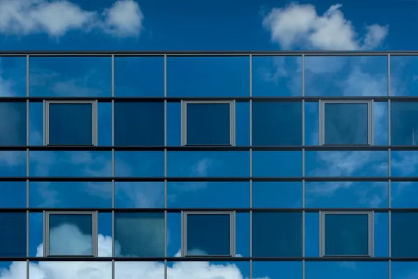 Modern glass building facade with reflective windows and metal framework