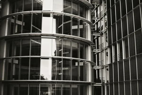 Modern curved glass building exterior with multiple reflective windows and metal frames