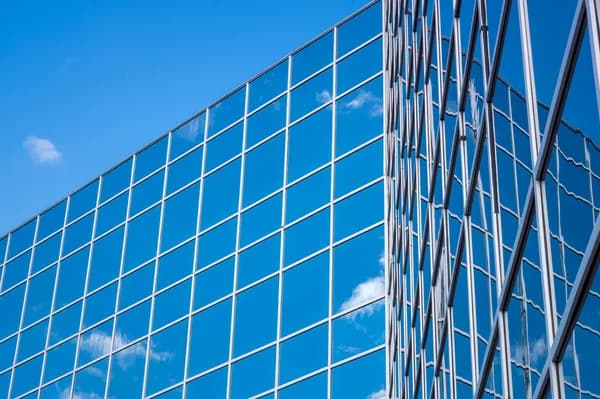 Modern glass building facade with reflective windows and metal frame structure