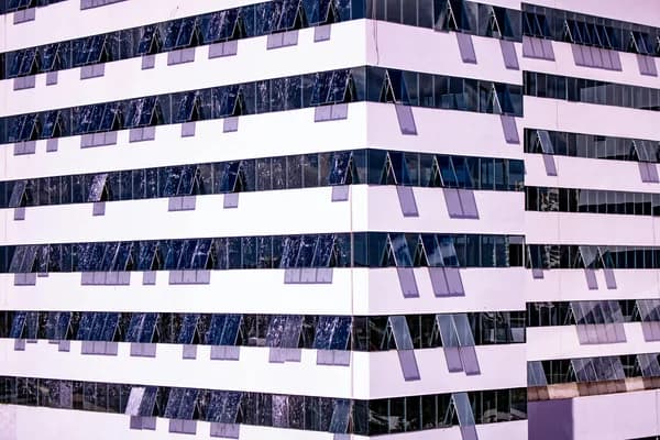 Modern striped building facade with reflective glass windows and solar panels