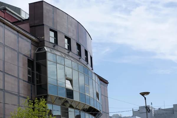 Modern office building exterior with large curved glass windows and dark facade