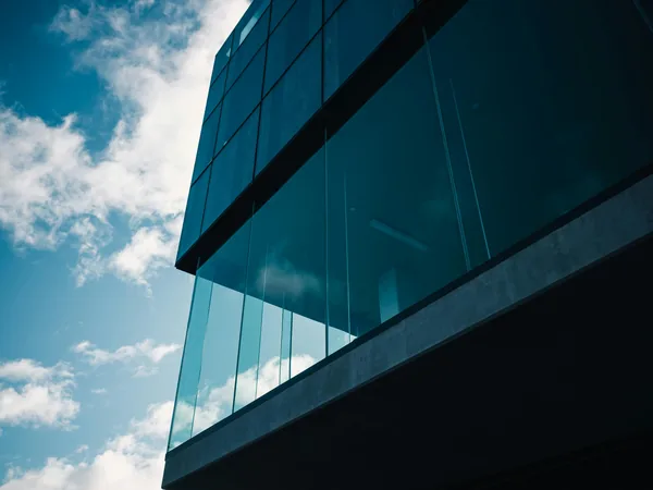 Modern glass building facade with reflective windows and blue sky