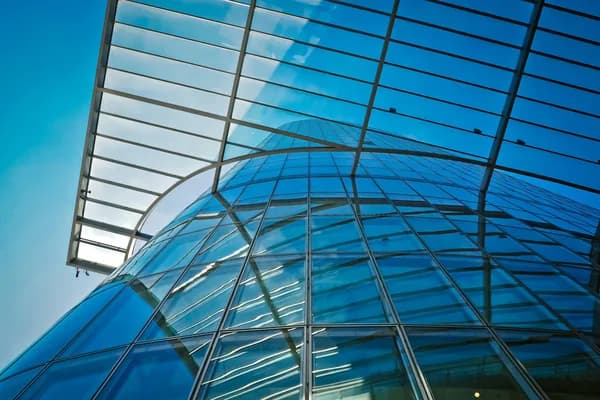 Modern curved glass building facade with reflective windows and steel framework