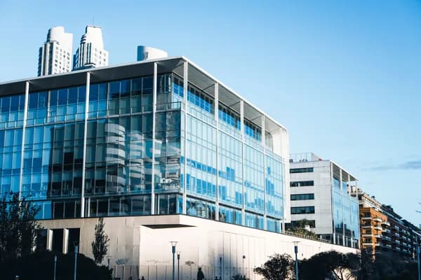 Modern glass-facade office building with blue-tinted windows and steel framework
