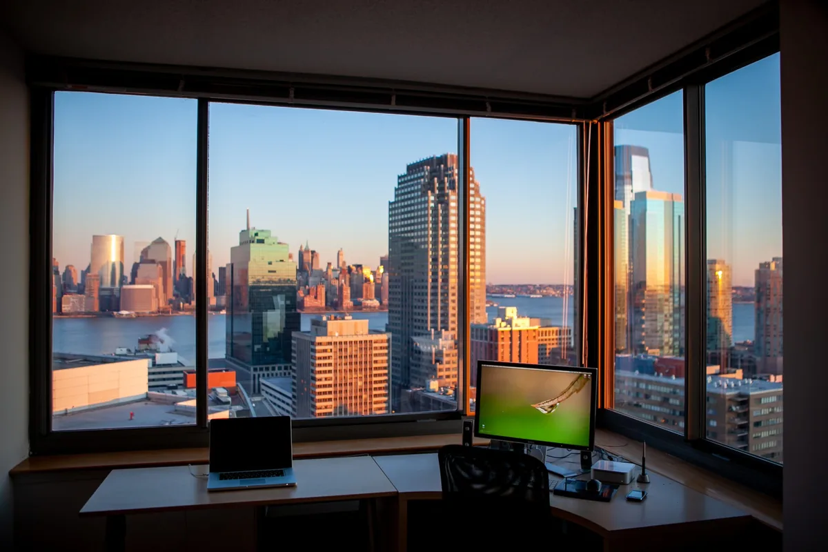Modern office workspace with computers overlooking urban skyline through large windows