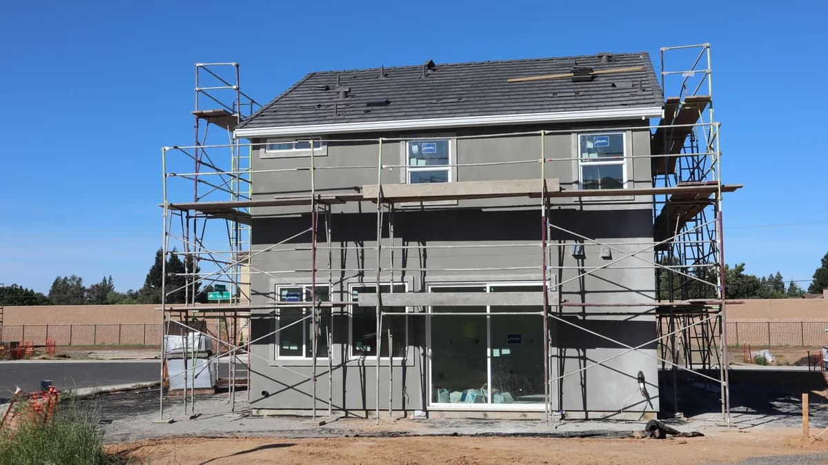 Multi-story building under construction with metal scaffolding and protective coverings