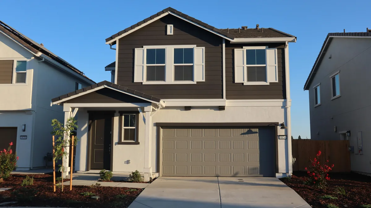Modern two-story residential home with large windows and beige exterior siding