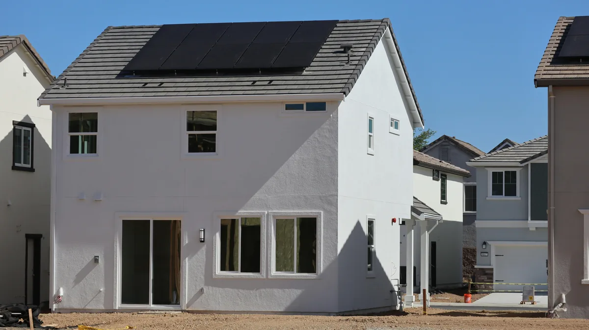 Modern white two-story residential home with solar panels and large windows