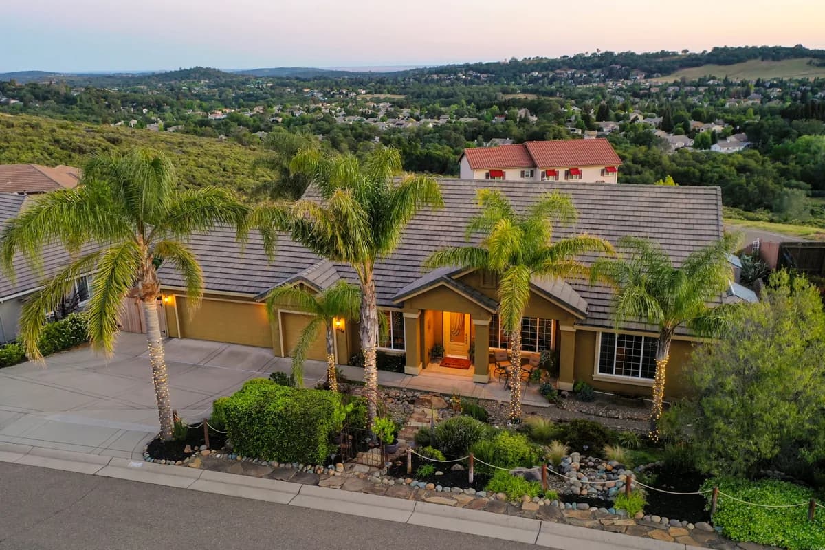 Luxury residential home with palm trees and manicured landscaping at dusk