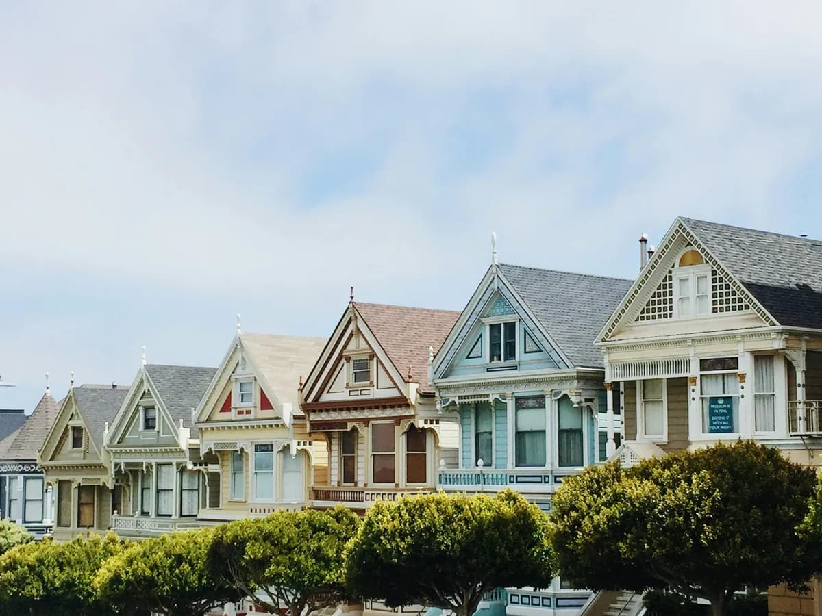 Row of Victorian houses with large windows and manicured hedges