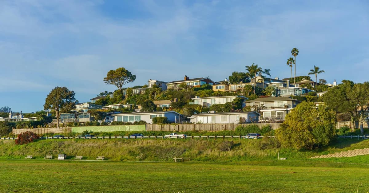 Hillside residential neighborhood with multi-story homes and manicured lawns