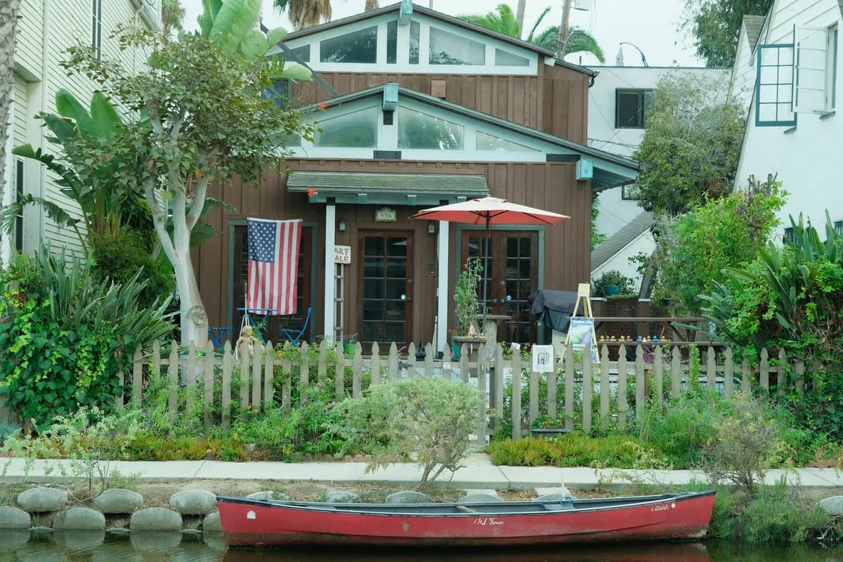 Waterfront cottage with white picket fence and moored red boat