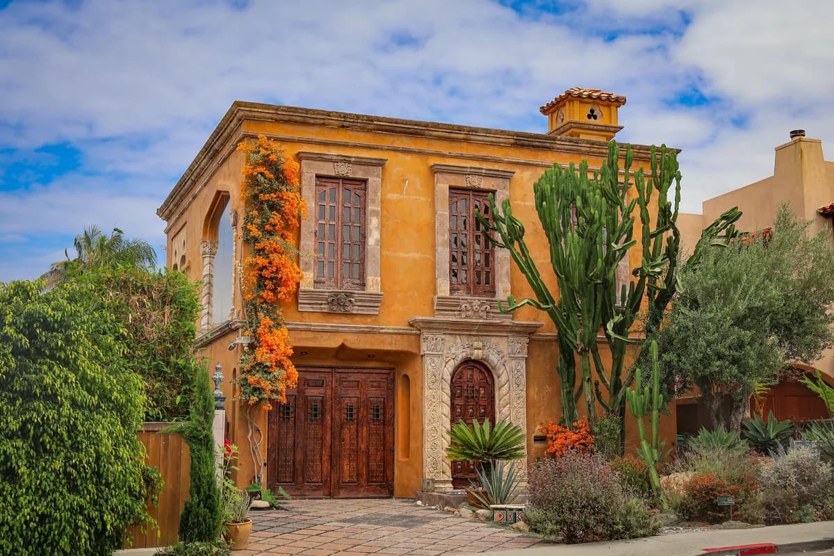 Historic orange stucco building with wooden doors and desert plants landscaping