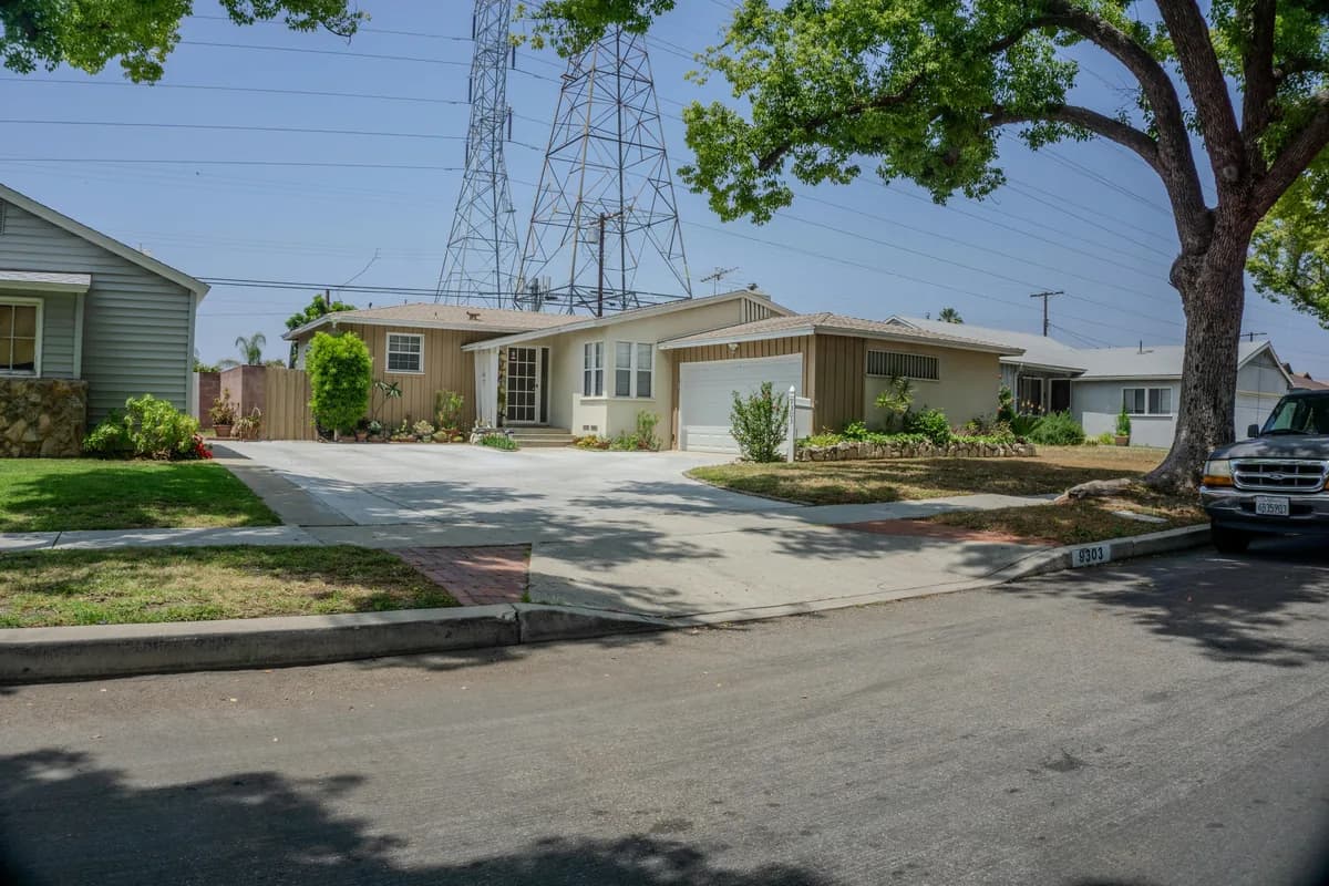 suburban residential street with single-story homes and large shade tree