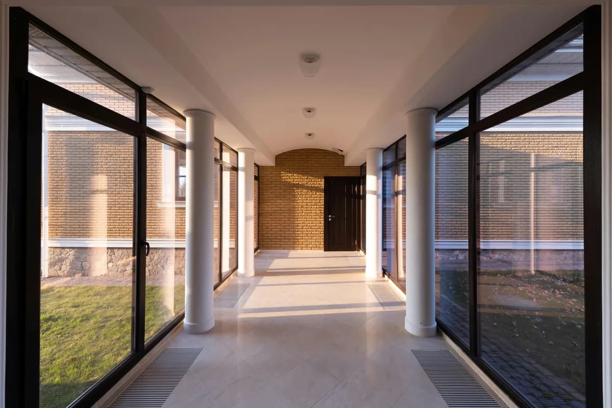 Modern hallway with large floor-to-ceiling windows and white columns