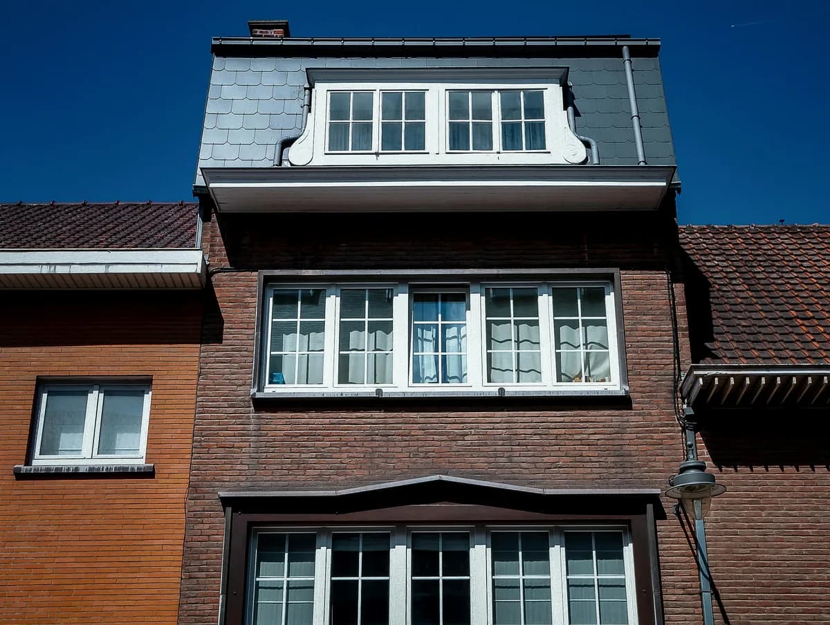 Multi-story brick building facade with multiple white-framed windows requiring cleaning