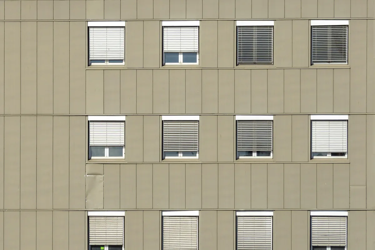 Modern residential building facade with multiple windows and closed blinds