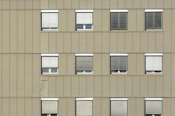 Modern residential building facade with multiple windows and closed blinds