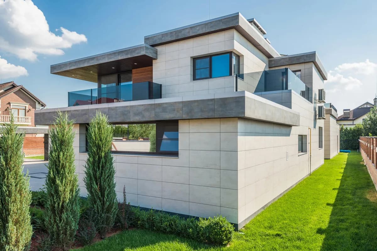 Modern residential house with large windows and glass balconies on sunny day