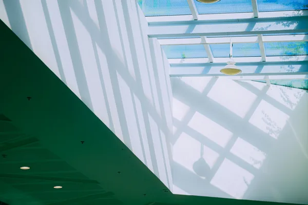 Bright skylight ceiling with geometric shadow patterns from structural beams