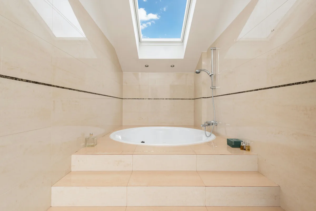 Modern bathroom with sunlit skylight window above soaking tub