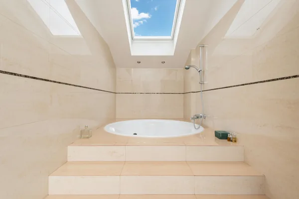 Modern bathroom with sunlit skylight window above soaking tub