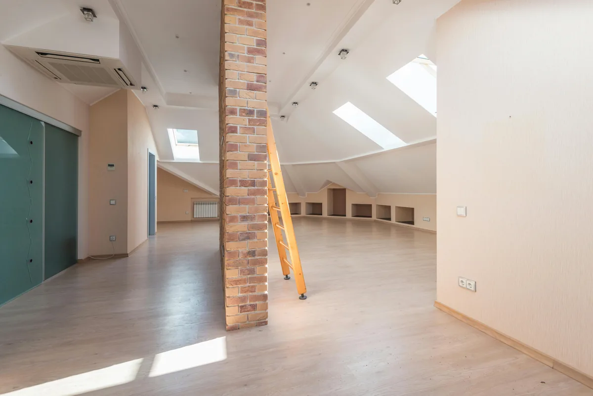 Interior attic space under construction with yellow ladder and brick support column