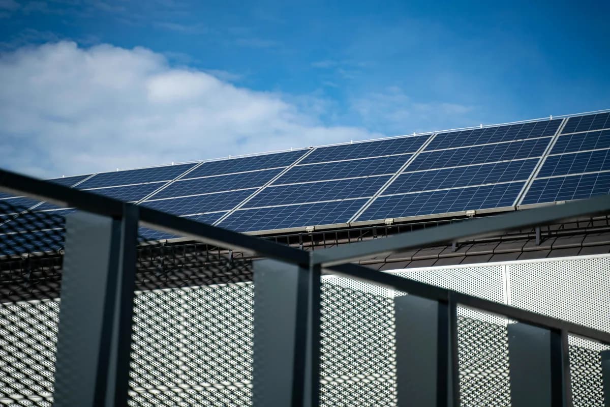Solar panels mounted on building roof with metal railing in foreground