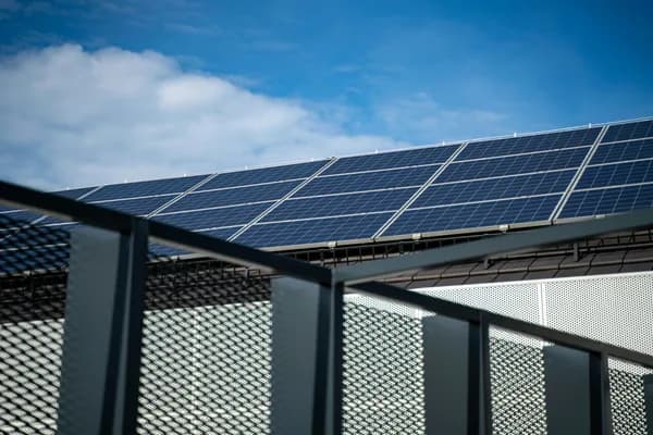 Solar panels mounted on building roof with metal railing in foreground