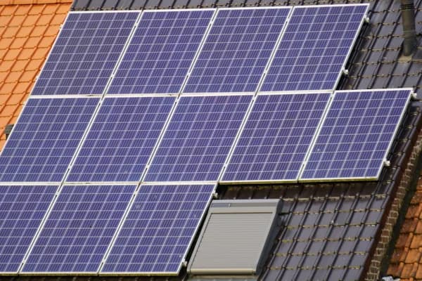 Solar panel array installed on residential rooftop with mixed tile roofing
