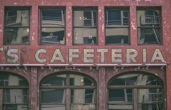 Weathered red brick building facade with rectangular windows and arched openings